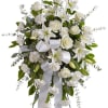 White floral standing spray with lilies, roses, and ribbon