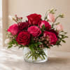 Red and pink roses arranged in a clear glass vase