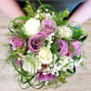Handheld bouquet of purple and white roses with airy filler flowers