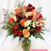 Mixed bouquet of red, peach, and white flowers in a glass vase