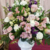 Large pastel bouquet of pink and white roses with purple flowers in a white vase
