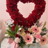 Heart-shaped red flower arrangement with pink blooms in a wooden box