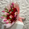 Bouquet of red roses and pink tulips wrapped in pale pink paper