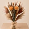 A stunning hand-tied bridal bouquet featuring pampas grass, dried florals, and warm