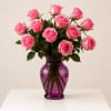 Pink roses arranged in a purple glass vase