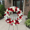 Red, white, and pink floral wreath on a stand outside a funeral home