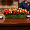 Large red and yellow floral centerpiece in a rectangular glass container