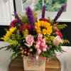 Colorful baby-themed flower arrangement in a white vase with pink ribbon