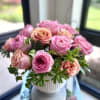 Pink and peach roses arranged in a white vase