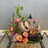 Basket arrangement with roses, mixed flowers, and a plush sloth