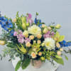 Mixed bouquet in a pink vase with blue, white, and peach flowers