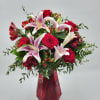 Bouquet of red roses and pink lilies in a red glass vase