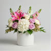 Pink lilies, roses, and white hydrangea in a white vase