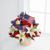 Basket arrangement of red carnations, white lilies, and small American flags