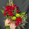 A striking and tall modern arrangement featuring vibrant red roses paired with
