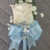 AN ELEGANT WHITE ROSE BOUTONNIERE ACCENTED WITH DELICATE BABY'S BREATH, SHIMMERING SILVER
