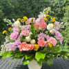 Mixed pink and white flowers in a white vase with yellow accents