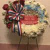 Memorial wreath with red roses, white and blue flowers, and a ribbon on a stand