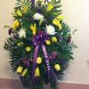 Standing funeral spray with yellow and white flowers and a purple ribbon
