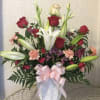 Bouquet of red roses and white lilies in a white vase with a pink ribbon