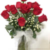 Red roses arranged in a glass vase with a white ribbon