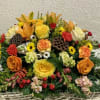 Large mixed floral arrangement with roses, lilies, and carnations in warm colors