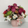 Mixed pink and white flowers in a pink vase with a floral ribbon