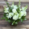 Arrangement of white roses, chrysanthemums, and snapdragons in a clear glass vase