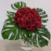 Red roses with glossy tropical leaves and white accents in a clear