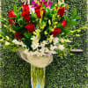 Tall bouquet of red roses and white orchids in a clear glass vase