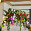 Tall tropical floral centerpieces with orchids and red blooms in glass vases