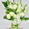 White roses and lilies arranged in a green-striped glass vase