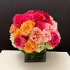Bouquet of pink, peach, and orange roses in a square glass vase