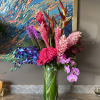 Tropical bouquet in a tall glass vase with pink orchids and bright mixed blooms