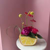 Bright pink and magenta roses cluster low in a cheerful lemon-shaped ceramic