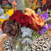 Mixed bouquet of roses, sunflowers, and purple flowers in a glass vase