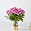Pink roses arranged in a clear glass vase with a gold base