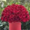 Round bouquet of red roses in a pink cylindrical box