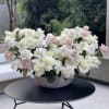 Large bowl arrangement of white and blush roses on a table