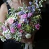 Woman holding a pastel bouquet of pink and purple flowers