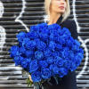Woman holding a large bouquet of vivid blue roses