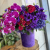 Purple and pink bouquet with orchids, roses, and hydrangeas in a purple vase