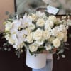 Large white bouquet of roses and orchids in a white box