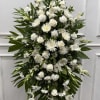 Tall white funeral spray with roses, chrysanthemums, and lilies