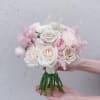 Handheld bouquet of pale pink and white roses with soft filler flowers