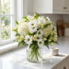 White daisies and pale blooms arranged in a clear glass vase