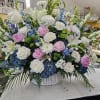 A sweep of soft blue hydrangeas and blushing pink peonies tops a