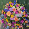 A lush, garden-style casket spray that brings a bright, comforting presence during