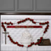 Red rose funeral casket spray with memorial ribbon and crucifix