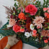 Colorful bouquet with roses, daisies, and mixed blooms beside orange plates